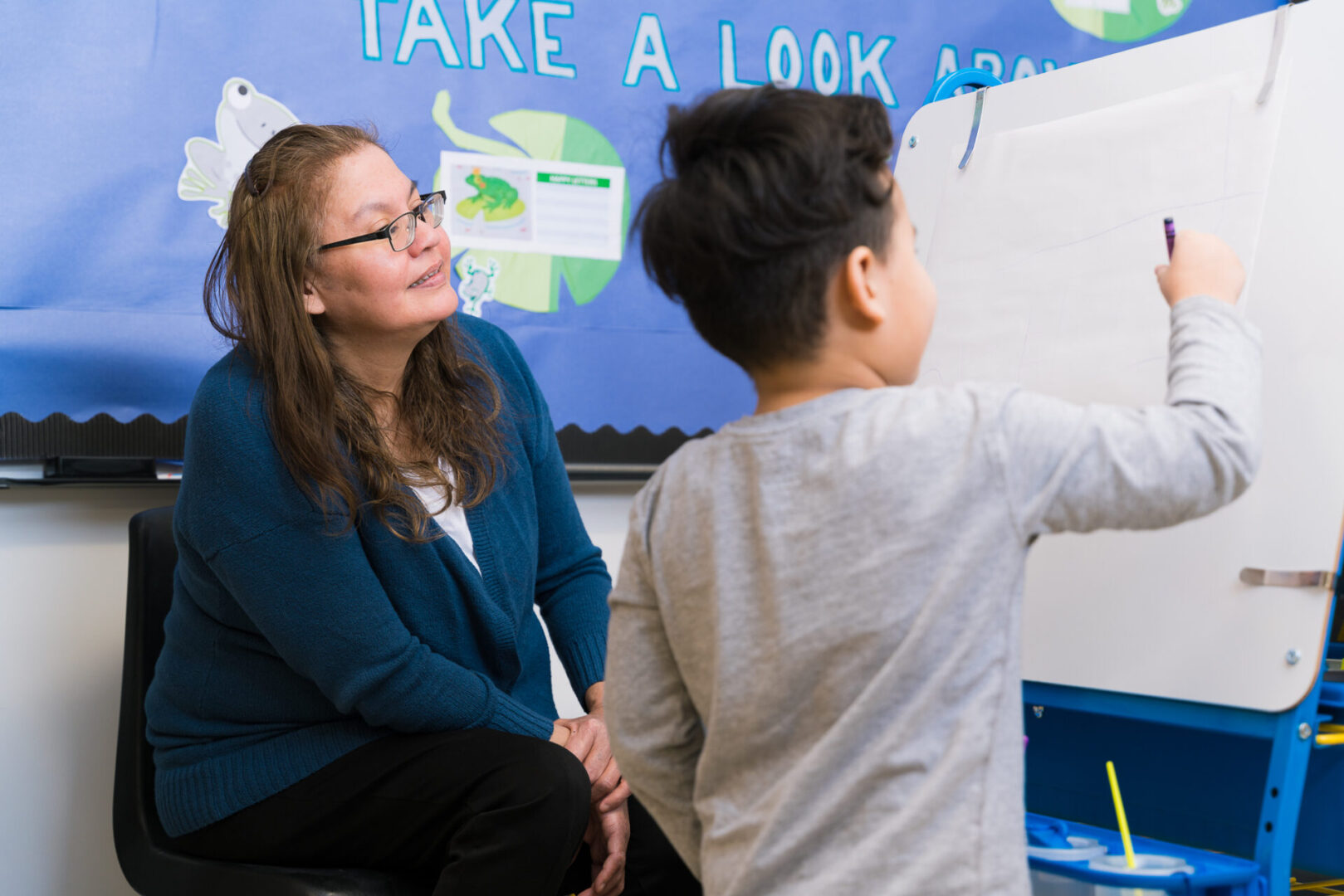 Woman teaching child at a small whiteboard.