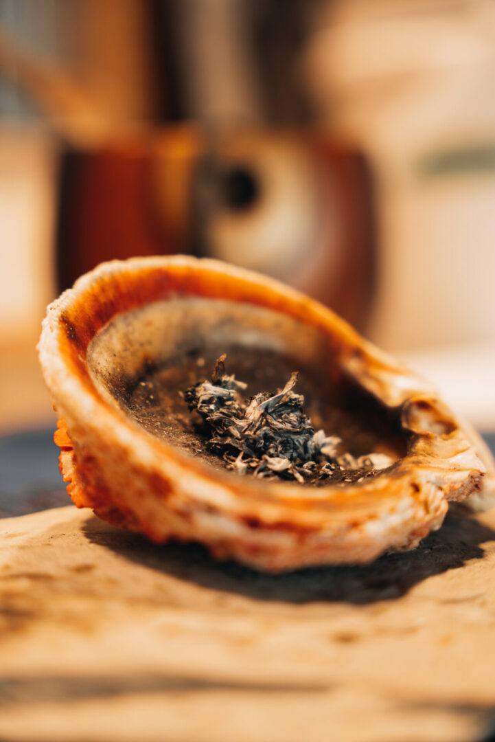 Picture of a half oyster shell with smoking tobacco.