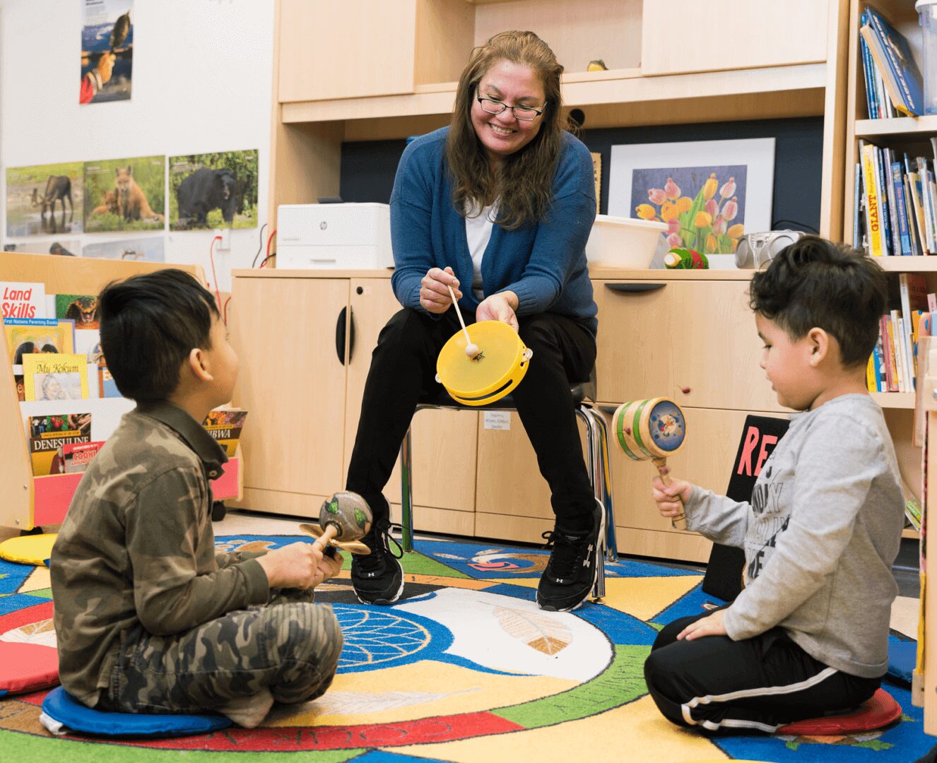 ECE student drumming on a small drum with two children