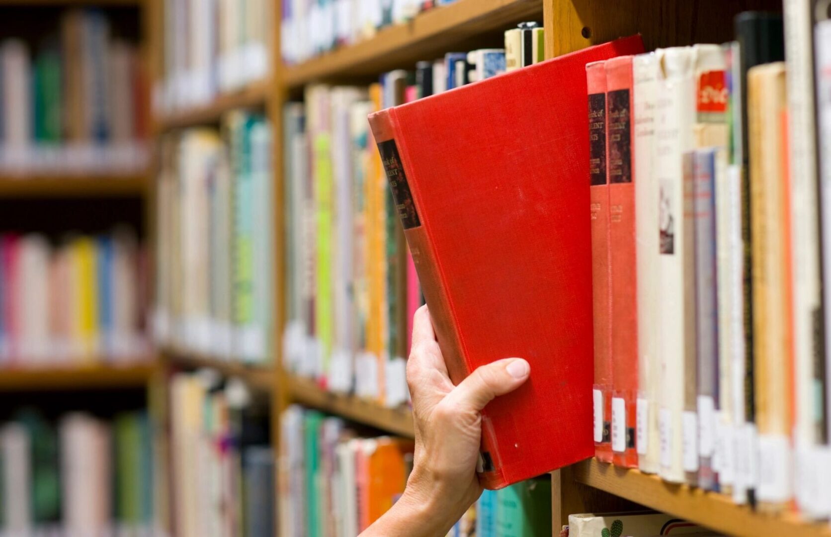 stock photo of a book being pulled from a library shelf